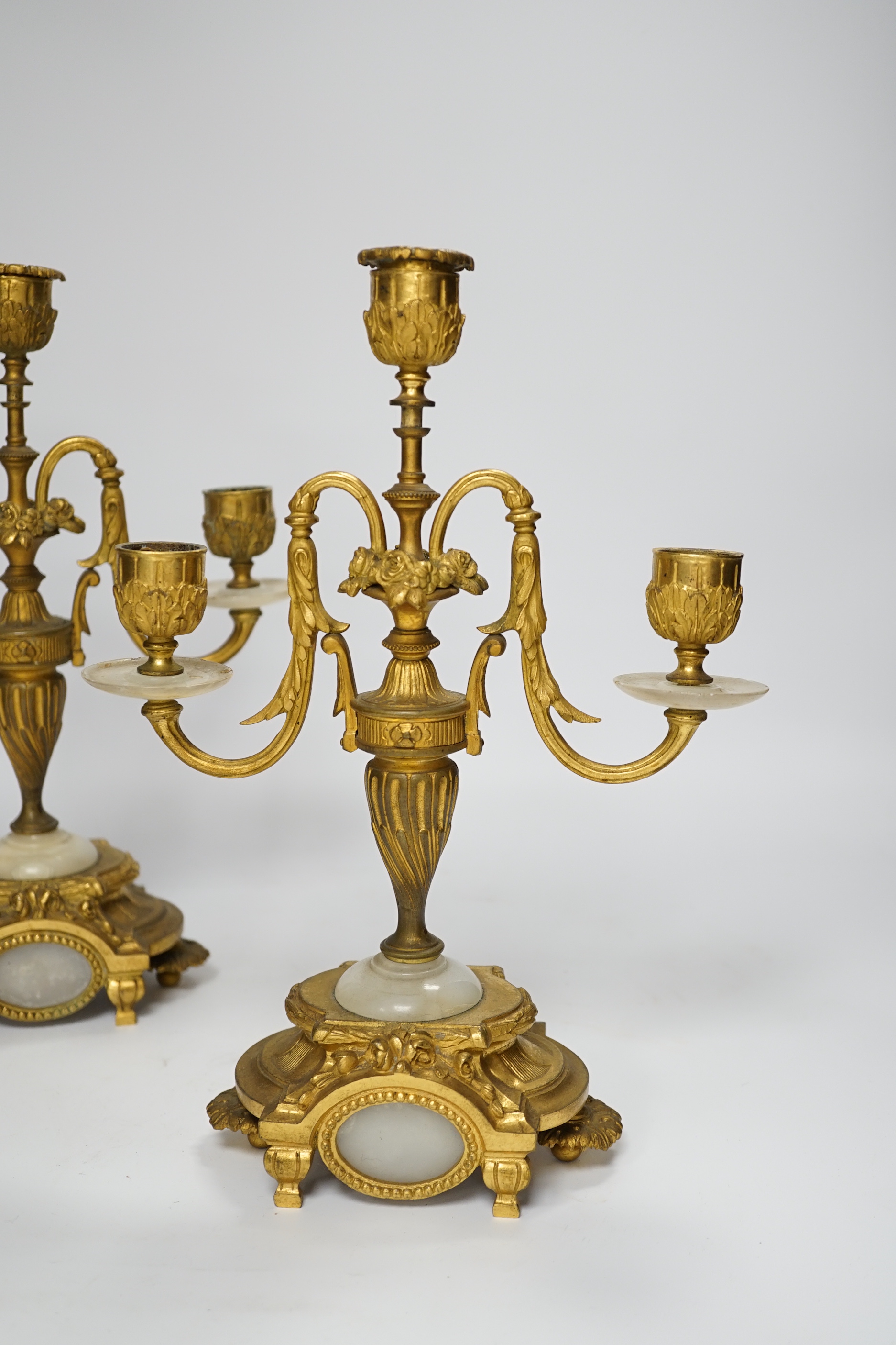 A pair of Louis XVI style ormolu and white onyx three branch candelabra, 29cm high